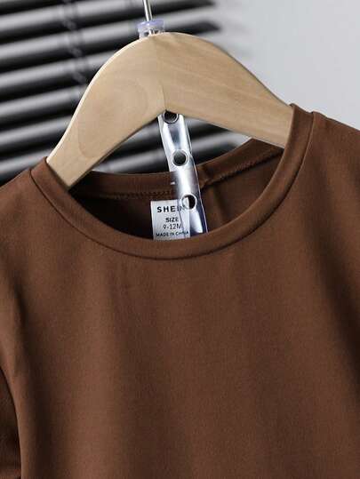 مجموعة الأطفال الحياد الجنسين المولود الجديد قطعتين. هي مجموعة مع ملابس علوية بني وشورت لون المشمش، مزينة برقع بالحروف. مناسبة للصيف، هذه الملابس الرياضية مثالية للعطلات والحفلات والرحلات وكمستلزمات أساسية متعددة الاستخدامات للمدرسة في الصيف. ملابس الأطفا