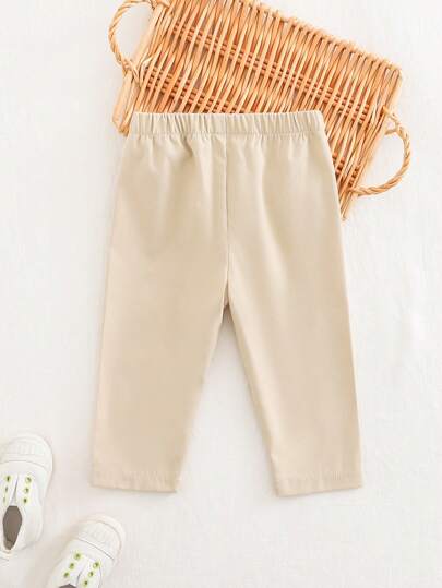 SHEIN سراويل سوداء للأطفال الرضع، مناسبة للأولاد والبنات، تصميم أسود متعدد الاستخدامات يمكن ارتداؤه في أي موسم، أزرار زخرفية في الوسط الأمامي تضيف تفاصيل تصميمية، ملابس أطفال محايدة اللون