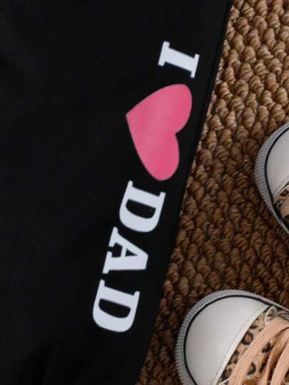 SHEIN طقم ملابس رياضية كاجوال للأطفال الرضع البنات والأولاد، يتكون من تي شيرت أسود بأكمام قصيرة مطبوع عليه "أحب أمي" على الصدر، وبنطال رياضي أسود مطبوع عليه "أحب أبي" على الساق، مناسب لارتداء في عيد الأم والأب واليومي والمدرسة