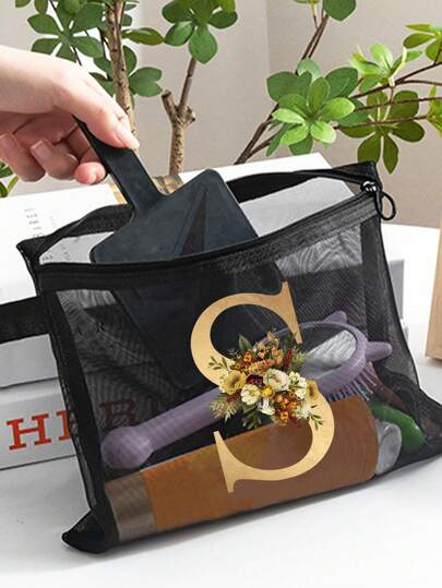 حقيبة مكياج شفافة من الشبكة المعدنية مع طباعة زهرية وأحرف ذهبية، مثالية للصيف. لها طراز وتمكن استخدامها كحافظة أقلام. مجهزة بسحاب إغلاق، هذه الحقيبة قابلة للطي، خفيفة الوزن وتتميز بتصميم مقاوم للبهتان.