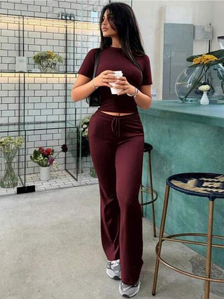 بذلة رياضية للنساء في الربيع ، تتكون من ملابس علوية ذو أكمام قصيرة مكشوف البطن ، وبنطال رياضي متقلص مصمم بنمط مزخرف بالدانتيل