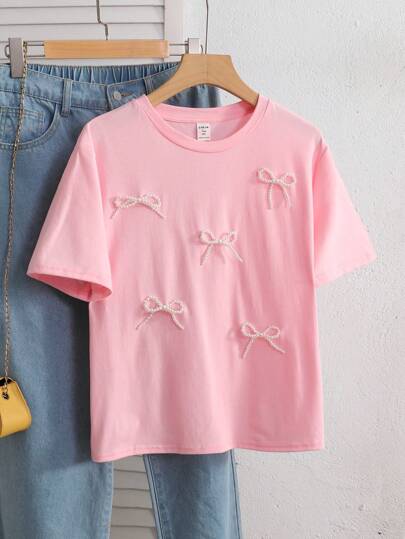 ملابس بناتي قميص T-shirt أنثوي للمراهقات من اللون الوردي بياقة مستديرة وأكمام قصيرة، بخامة مضفر بخرز ولمسة فيونكة