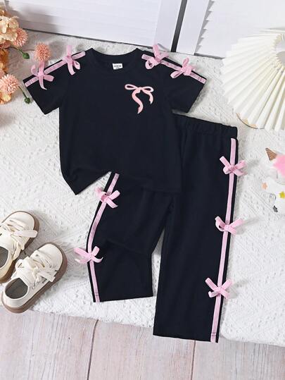 SHEIN مجموعة فستان من 2 قطعة للبنات صيف ربيع، ملابس علوية قصيرة الأكمام ذات ياقة دائرية باللون الأسود أنيقة مزينة بفيونكة زهرية واللون الوردي وبنطلون مطابق، مناسب للعب في الخارج والاستخدام اليومي
