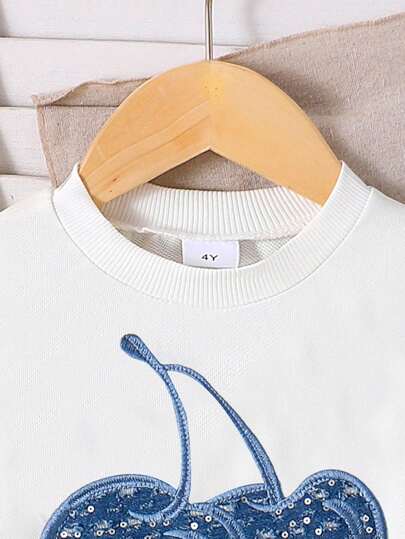 SHEIN طقم بناتي مكون من بلوزة كروشيه طويلة الأكمام بياقة مستديرة مع رقعة جينز وشعار الكرز، وتنورة جينز مطوية، طقم أزياء خريفي أنيق باللون الأزرق الفاتح لفتيات الأطفال