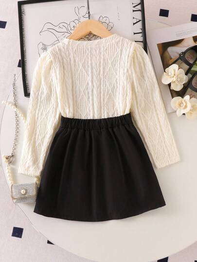 SHEIN Elladie kids طقم تي شيرت وتنورة صغيرة سوداء مريحة للفتيات الصغيرات، التي تتكون من بلوزة بياقة دائرية وأكمام طويلة بطبعات زهور بيضاء، مقترنة بتنورة سوداء مطوية