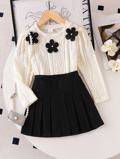 SHEIN Elladie kids طقم تي شيرت وتنورة صغيرة سوداء مريحة للفتيات الصغيرات، التي تتكون من بلوزة بياقة دائرية وأكمام طويلة بطبعات زهور بيضاء، مقترنة بتنورة سوداء مطوية