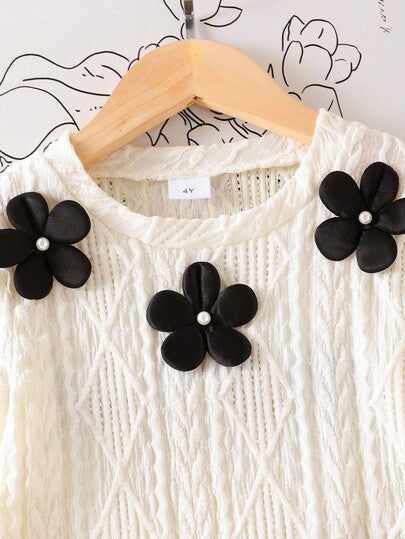 SHEIN Elladie kids طقم تي شيرت وتنورة صغيرة سوداء مريحة للفتيات الصغيرات، التي تتكون من بلوزة بياقة دائرية وأكمام طويلة بطبعات زهور بيضاء، مقترنة بتنورة سوداء مطوية