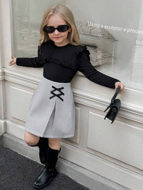SHEIN Elladie kids طقم تي شيرت وتنورة للفتيات الصغيرات، التي تتكون من ملابس علوية سوداء طويلة الأكمام مزينة بالكشكشة مع تنورة مزينة بفيونكة وذات حافة مشقوقة، مناسب للخريف والشتاء