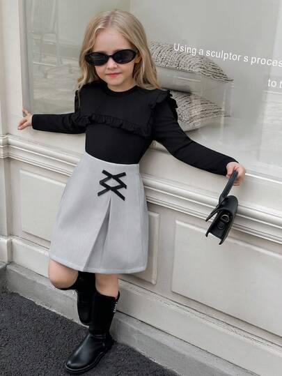 SHEIN Elladie kids طقم تي شيرت وتنورة للفتيات الصغيرات، التي تتكون من ملابس علوية سوداء طويلة الأكمام مزينة بالكشكشة مع تنورة مزينة بفيونكة وذات حافة مشقوقة، مناسب للخريف والشتاء