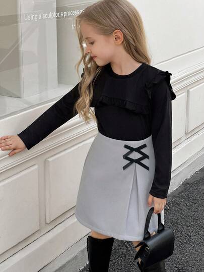 SHEIN Elladie kids طقم تي شيرت وتنورة للفتيات الصغيرات، التي تتكون من ملابس علوية سوداء طويلة الأكمام مزينة بالكشكشة مع تنورة مزينة بفيونكة وذات حافة مشقوقة، مناسب للخريف والشتاء