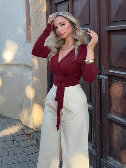 Jeta Ari قميص رياضي مقصر ضيق بأكمام طويلة وياقة على شكل حرف V، قطعة أساسية في خزانة ملابس المرأة ذات تصميم أنيق وعصري، مناسب لفصلي الربيع والخريف