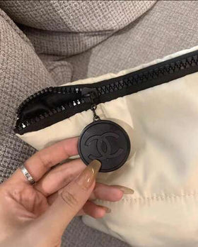 CHANEL حقيبة تخزين ناعمة مربعة بيج اللون، حقيبة مكياج، مزينة بطباعة دائرية ثلاثية الأبعاد بحرف C مزدوج، مع سحاب أسود وتفاصيل معلقة دائرية، سعة كبيرة لتخزين مستحضرات التجميل والعناية بالبشرة، محمولة وخفيفة الوزن، مناسبة للتنقل اليومي وترتيب المنزل والخروج