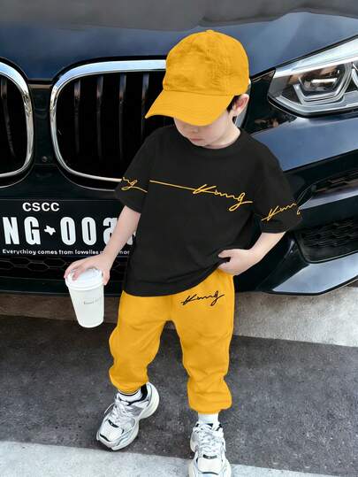 SHEIN Streecool Kids مجموعة ملابس للأولاد الصغار 2 قطعة، تي شيرت أسود بياقة مستديرة وبنطال أصفر، طباعة حرفية وجرافيكية عصرية، ملابس كاجوال مريحة مناسبة لجميع الفصول